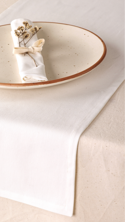 Ceramic plate with a folded napkin and small bouquet on a light beige tablecloth.