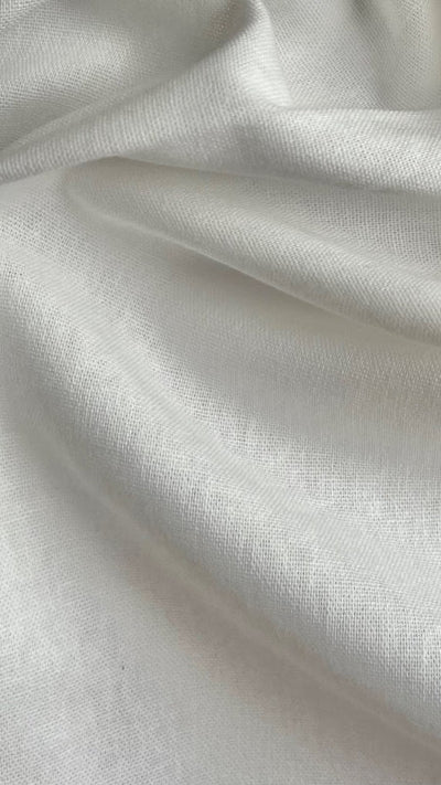 A close-up view of a yard of white, recycled cotton woven fabric with a soft texture.
